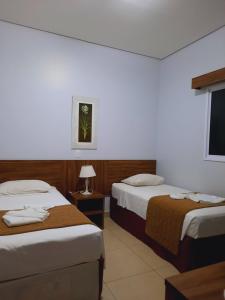 a hotel room with two beds and a flat screen tv at Casa Jardins da Lagoa in Caldas Novas