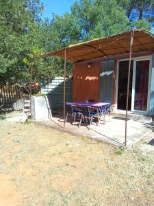 un patio con una mesa púrpura y sillas debajo de una tienda de campaña en Mes deux Gîtes de l'Ocre en Villars