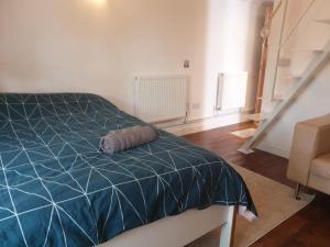 a bedroom with a bed with a blue comforter at Mezzanine studio apartment (U9) in London
