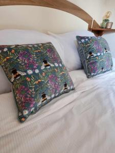 two pillows with birds on them sitting on a bed at Eden Breaks, Mallard Lake in Cirencester