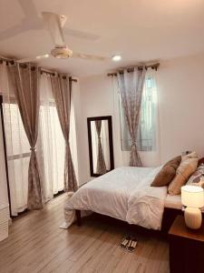 1 dormitorio con 1 cama grande y 2 ventanas en The Cozier, the Better at Oysterbay, en Dar es Salaam