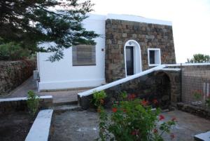 a house with a stone wall next to a building at sull'arco dell'elefante in Pantelleria