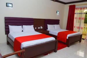 una camera con due letti con lenzuola rosse e bianche di White Peacock Resort Mtwapa a Mtwapa