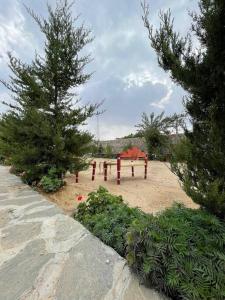 a garden with trees and a table in the sand at Al Hada Hills Residential Unit in Al Hada