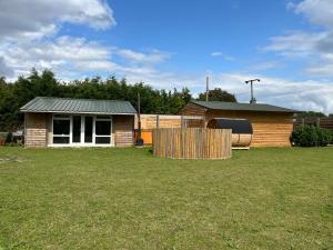 a house with a fence in front of a yard at Wind In The Willows Luxury Glamping in Peterborough