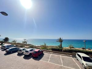 Una fila de autos estacionados en un estacionamiento cerca del océano en The Symphony of the Breeze en Netanya