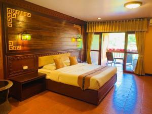 - une chambre avec un grand lit et une tête de lit en bois dans l'établissement ดอยหมอกดอกไม้รีสอร์ท DoiMok DokMai Resort, à Mae Salong