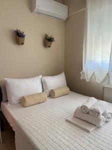 1 dormitorio con 1 cama con toallas y ventana en Stergios_Apartments 01, en Kozani