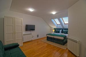 a bedroom with a bed and a couch and a tv at Stross Apartments & Rooms in Osijek
