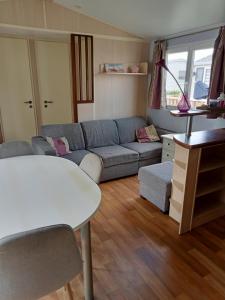 a living room with a couch and a table at Stacaravan met eigen terras en tuin 6personen in Bredene