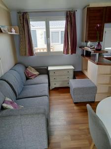 a small living room with a couch and a table at Stacaravan met eigen terras en tuin 6personen in Bredene