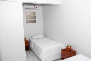 a white bedroom with a bed and a window at Novo Hotel in Boa Vista