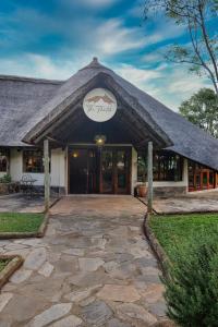 a building with a thatched roof with a patio at Leopards Hill Lodge in Lusaka