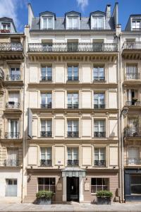- un grand bâtiment beige avec des fenêtres et des balcons dans l'établissement Hotel Le Saint Gregoire, à Paris