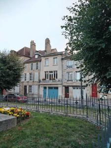 a building with a fence and flowers in front of it at Maison Diderot in Langres