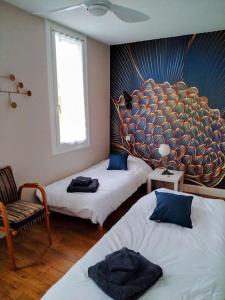 Habitación con 2 camas y una pintura en la pared. en Maison Diderot en Langres