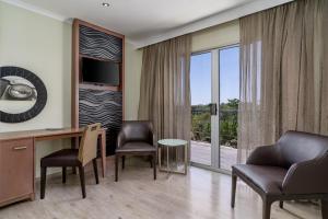 a hotel room with a desk and chairs and a large window at Protea Hotel by Marriott Upington in Upington