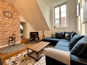 a living room with a blue couch and a brick wall at Belle Isle - Grand appart - 6 Places - T3 - 72m2 in Metz