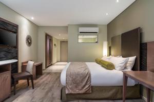 a hotel room with a large bed and a desk at Protea Hotel by Marriott Upington in Upington