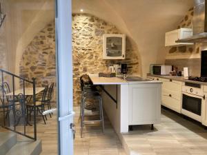 a kitchen with a table and a stone wall at Sab et Mica in Les Fumades-Les Bains