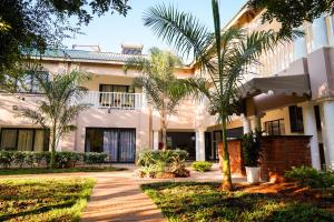 a building with palm trees in front of it at Pristine deluxe room with kitchen and pool - 2147 in Victoria Falls