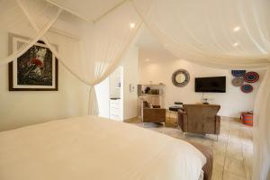 a white bedroom with a bed and a desk at Pristine deluxe room with kitchen and pool - 2147 in Victoria Falls