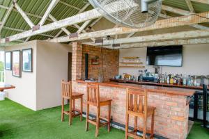 um bar de tijolos com três cadeiras de madeira em Modern deluxe with kitchenette and pool - 2148 em Victoria Falls