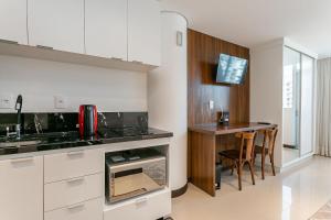 uma cozinha com armários brancos e uma mesa com cadeiras em Vista Mar com Sacada na Agronômica #CA49 em Florianópolis