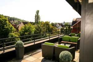 einen Balkon mit grünen Stühlen und Pflanzen auf einem Gebäude in der Unterkunft Hotel Alpha in Stuttgart