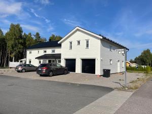 a white house with two cars parked in a parking lot at 2 bedroom apartment in Falun - 2km from centrum in Falun
