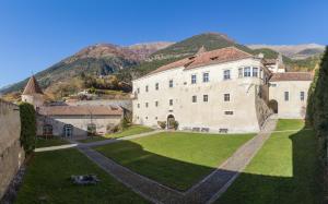an aerial view of a building with mountains in the background at Schloss Goldrain - Bildungshaus Gästehaus in Coldrano