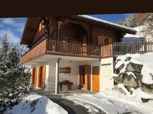 um chalé de madeira com uma varanda na neve em Dorril SUNNY & QUIET chalet 10 pers by Alpvision Résidences em Veysonnaz