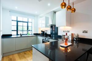 a kitchen with white cabinets and a black counter top at Stunning Townhouse with Pool Table in Birmingham