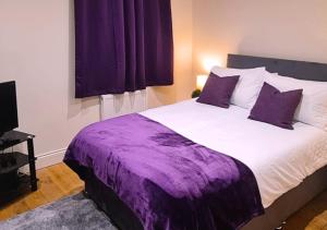 a bedroom with a large bed with purple sheets at Modern 2 Bedroom Apartment in Peckham London in London