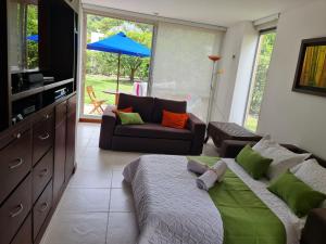 um quarto com uma cama, um sofá e um guarda-chuva em ACATA - Condominio Campestre / Casa em Villeta