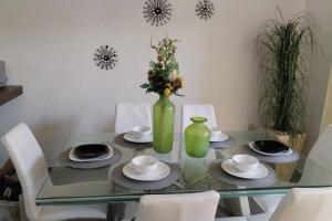 casa green con club de alberca في تيبيك: طاولة زجاجية مع مزهرية خضراء بها زهور
