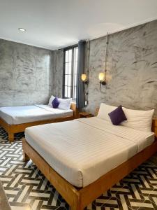 プーケットタウンにあるナ サイアム ゲストハウスの紫色の枕が備わる客室内のベッド2台