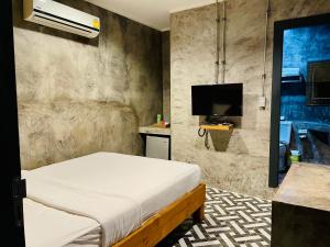 a bedroom with a bed and a flat screen tv at Na Siam Guesthouse in Phuket Town