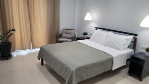 a bedroom with a large bed and a chair at Crete Apart House - South in Ayía Marína