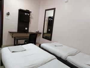 a hospital room with two beds and a mirror at Hotel Satyam in Jaigaon