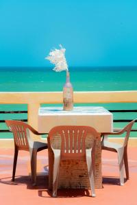 a table with a vase and two chairs and the ocean at Hotel Flamingos Inn in Chuburná