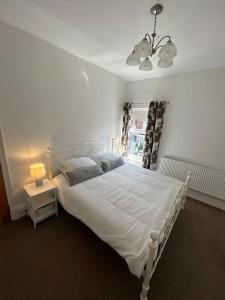 a bedroom with a white bed and a window at Beautiful 4BR Home near Chester Racecourse in Chester