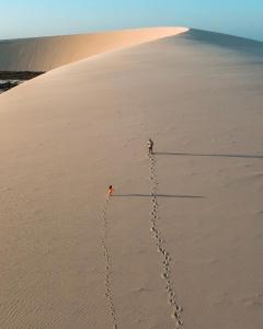 a person and a dog walking on the beach at Vila hangloose pôr do sol in Acaraú