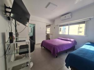 1 dormitorio con 1 cama y TV. en Av. Corrientes 1670 - Paseo La Plaza - en Buenos Aires