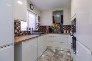 a kitchen with white cabinets and a clock on the wall at Lovely Two Bed at Tanglewood in Hillingdon
