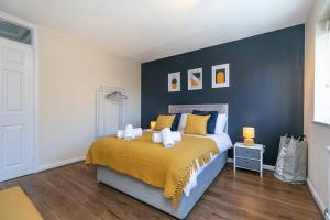 a bedroom with a bed with a blue wall at Lovely Two Bed at Tanglewood in Hillingdon