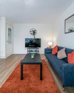 a living room with a blue couch and a table at Lovely Two Bed at Tanglewood in Hillingdon