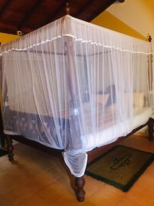 a bed with white curtains on top of it at MALLI'S VILLA in Koggala