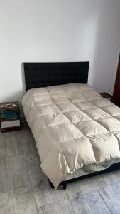 1 cama grande en un dormitorio con una pared blanca en Departamento en General Paz en Córdoba