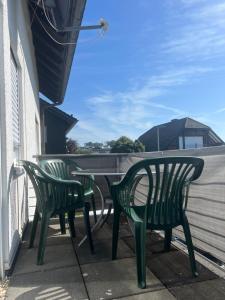 two green chairs and a table on a balcony at F&M Wohnungen in Olpe in Wenden